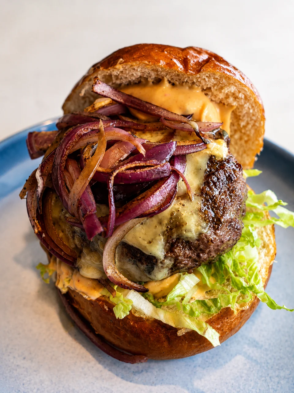 A burger with cheese, red onion and lettuce