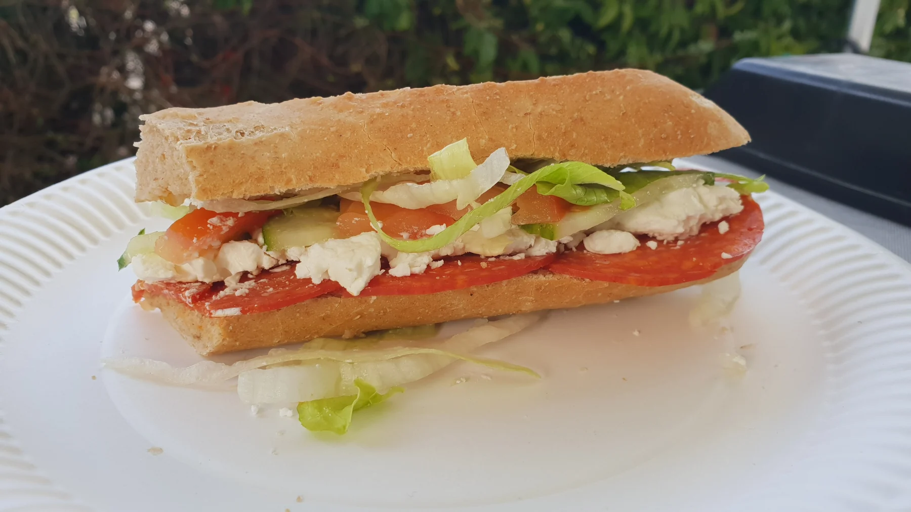 A long baguette filled with salad, tomato and cheese
